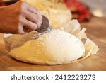 Small photo of Bread scoring. Close up photo with a male hand scoring the sourdough bread before cooking the home made bread. Bakery at home. Wheat flour dough scoring. How to score the bread with a blade.
