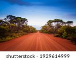 Empty open outback road in Western Australia. Straight single lane dirt road stretching into the distance. Desert scene, Endless travel and adventure.
