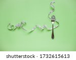 Diet and healthy eating concept. Top view of weightloss. Measuring tape on a fork. Green background