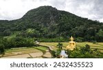 Small photo of PHRAE , THAILAND - DEC 4 , 2023 : Top view of Phra Chao Ton Luang is outdoor Buddha statue. Sitting prominently in the middle of the rice field Inside Wat Nakhuha there are beautiful natural places.