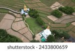 Small photo of PHRAE , THAILAND - DEC 4 ,2023 :Top view of a bamboo bridge to white pagoda and Phra Chao Ton Luang outdoor Buddha statue. Sitting in the a rice field at Wat Nakhuha there are beautiful natural places