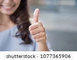 successful girl pointing thumb up sign gesture; portrait of cheerful smiling woman pointing up approving, yes, ok, good, thumb up gesture; asian woman young adult model