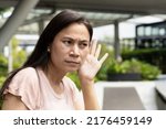 Small photo of Middle aged asian senior woman listening to rumor, gossip, hearsay, concept image of fake news, propaganda or news manipulation