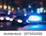 Small photo of Selective focus on blue flasher light of siren. Police car at night city street. Themes crime, emergency and help.