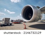 Preparation freight airplane at airport. Loading of cargo containers against jet engine of plane.