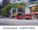 Small photo of Fast moving fire engine on city street. Firefighters in blurred motion. Themes rescue, urgency and help.