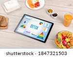 Organic food and tablet pc showing DETOX inscription, healthy nutrition composition