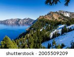 View of Garfield Peak, a popular destination hike inside of Crater Lake National Park, seen with blue skies and sunny conditions with a bit of snow left late into spring
