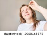 Small photo of Young woman doing morning routine. Home maternity treatment. Health care concept. Female person. Eyedrop glaucoma concept. Eyewash treatment. Yellow drop