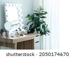 Small photo of Table with a mirror bulbs at make up room, used while dressing or applying makeup, cosmetic brushes in cup and markup set on dressing table