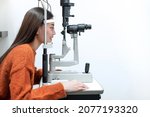 Small photo of Asian beautiful woman doing eye test with slit lamp in modern ophthalmology clinic, side view, checking retina of a female eye