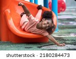 Happy African child girl sliding and playing at outdoor playground in the park on summer vacation, outdoor activity at school or or playground