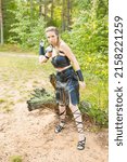 Small photo of long-haired mediaeval brigand wearing black leather armour with sharp morglay in her hand defends a path in the spring wooden