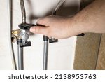 plumber hand installs water stop tap by adjustable wrench at home