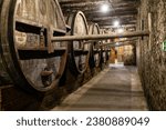 Small photo of Yerevan, Armenia - October 2, 2023: old wood brandy barrels and ancient city fortress wall in basement of NOY brandy factory in Yerevan