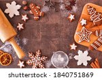 Christmas baking frame with gingerbread cookies. Top view over a dark stone background with copy space. Holiday baking concept.