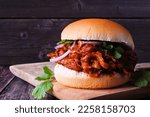 Small photo of Jack fruit meatless burger against a dark wood background. Healthy eating, plant-based pulled pork meat substitute concept.