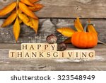 Happy Thanksgiving wooden blocks against a rustic wood background with pumpkins and autumn leaves