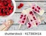 Group of homemade raspberry vanilla popsicles on a rustic white wood background