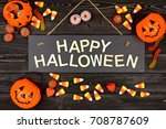 Happy Halloween black sign with wood letters and frame of candy on a black wood background
