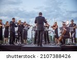 Orchestra playing classic instrumental music under cloudy sky