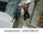 Fashion. Young stylish woman walking on the city street looking aside smiling happy