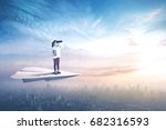 Picture of a little girl flying above a city with a paper plane while holding a book and using binoculars