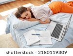school, education and laziness concept - tired teenage student girl with laptop computer and notebooks sleeping on bed at home