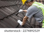Small photo of Worker man using waterproof roof coating repair to fix crack of the old tile roof.