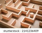 Small photo of Wooden blocks maze game with wooden ball as subject to find the exit, complicated issue, busy and complex event