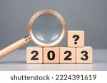 Small photo of 2023 wood cubes with question symbol and magnifying glass, analysis what will happen in 2023, product review and forecast, trend concept