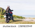 Small photo of Woman on a motorbike looking at the ocean view. Break on a trip off the beaten track