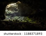 Small photo of Dark cave with a bright daylight spot of exit. Natural cave opening in Crimea. Entrance to the karst cave in a mountain. Inside the subterranean cave background with copy space.