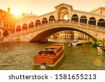 Rialto Bridge over the Grand Canal at sunset, Venice, Italy. It is a famous landmark of Venice. Boats sail under the Ponte di Rialto in summer evening. Sunny nice view of old architecture of Venice.