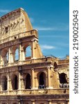 Small photo of Colosseum or Coliseum in Rome, Italy. Ancient Roman Colosseum is top tourist attraction in Rome. Vertical view of old Coliseum wall on blue sky background. Concept of sightseeing, travel and tourism.