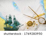Small photo of Golden sundial, antique W & HC 6" brass dividers calipers nautical navigation chart tool, parallel ruler, tall ship scale model, old white map close-up. Vintage still life. Sailing, travel accessories