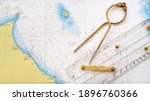 Small photo of Antique golden vintage W HC 6" brass dividers calipers nautical navigation chart tool, parallel ruler, old white chart close-up. Vintage still life. Sailing, travel accessories