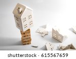 Small photo of Financial risk, unstable real estate investment and shaky housing market concept with a home on stacked wooden building blocks surrounded by the ruins and debris of another house that collapsed