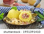 Potato dumplings stuffed with South Tyrolean bacon and served with sauerkraut in an iron pan 