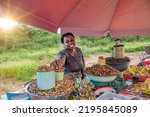 african street vendor selling peanuts, mopane worms and lollipops on the streets of the town