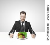 Small photo of businessman sitting on table and eating money proponent pie