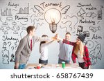 Young european team members hi-fiving each other above wooden desk. Brick wall with business sketch in the background. Teamwork concept