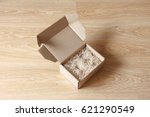 Opened cardboard box with wood excelsior shred filler on wooden background. View above