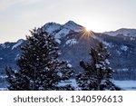 Small photo of High Idaho mountains sunset with a sun star and opine trees