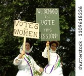 Small photo of LONDON/UK- JUNE 10th 2018: Two women dressed in historic outfits and carrying VOTES FOR WOMEN banners, attend the folk festival in barking, east London, to celebrate 100yrs of female suffrage.