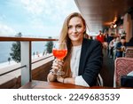 Young business woman drinking alcoholic cocktail. Happy alone woman in outdoor cafe or restaurant on sunny summer day, break for lunch between meetings.