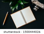Small photo of Top view of a flat lay open diary pen camera and green plant lies on a black table. Concept of a blogger and journalist. Place for text