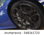 Stylish and expensive sports car closeup. Raindrops on a beautiful blue car. Black stylish sportcar alloy wheels with sports tires closeup