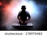 Disc jokey, DJ, silhouette over foggy illuminated background