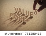 CORE VALUE wood word on compressed or corkboard with human's finger at S letter.
